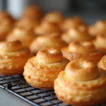 Pâtisseries craquelin choux dorées sur grille en lumière naturelle