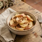 Bol en céramique rustique avec des tranches de pommes cuites à la cannelle sur une table en chêne, accompagné de deux petites fourchettes vintage