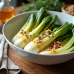 Endives vapeur végétariennes dans un bol en céramique avec sauce moutarde et miel, garnies de noix et thym frais sur table en bois rustique
