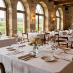 Salle de restaurant gastronomique en Val de Loire avec nappes blanches, verres en cristal et murs en pierre historique