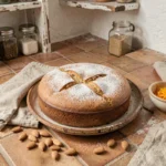 Tarta de Santiago espagnole sur assiette en céramique rustique avec sucre glace en forme de croix et amandes éparpillées dans une cuisine traditionnelle
