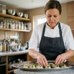 Traiteur indépendante arrangeant des amuse-bouches sur un plateau en inox dans une cuisine professionnelle équipée